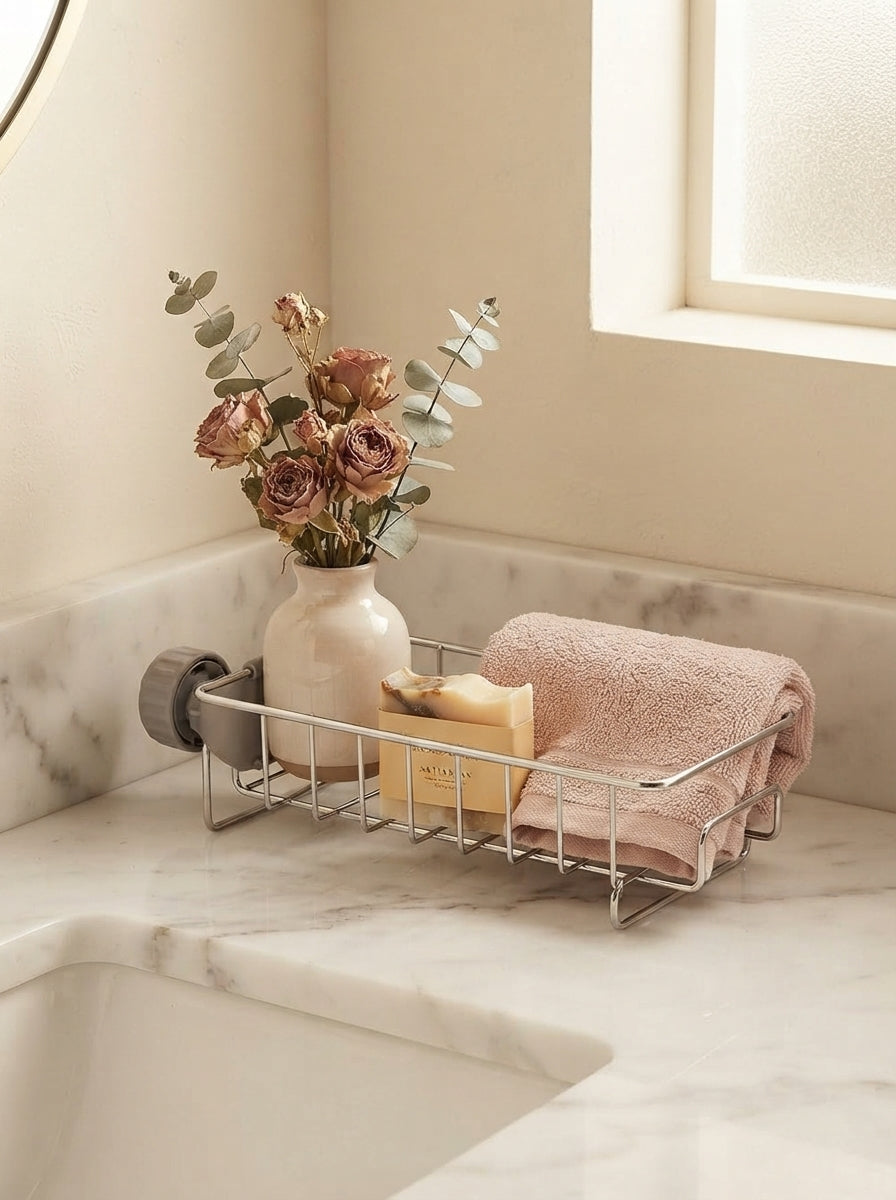 A minimalist sink caddy organizer on a marble countertop in a serene bathroom with rose and cream decor.